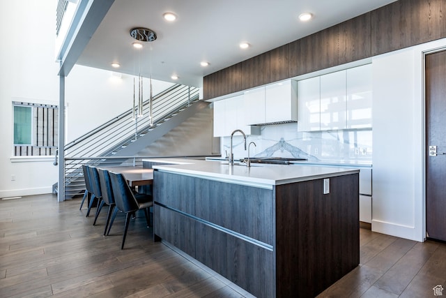 2752 W High Rd Unit 1501, Park City, UT 84098 - kitchen featuring an island with sink, white cabinetry, dark wood-type flooring, and backsplash