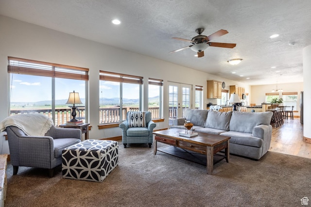 living room with ceiling fan, recessed lighting, wood finished floors, a mountain view, and a textured ceiling