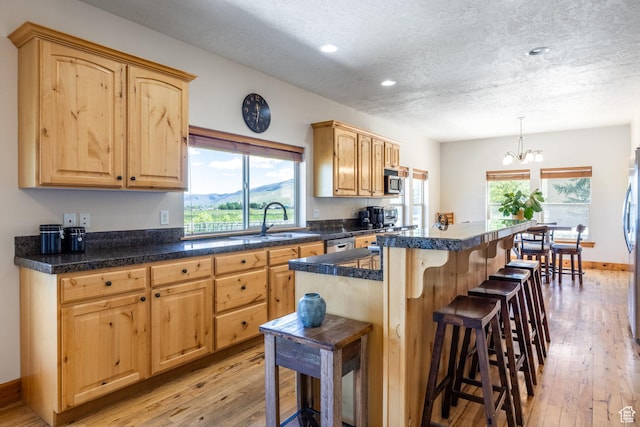 kitchen featuring light brown cabinets, appliances with stainless steel finishes, a breakfast bar, and a sink