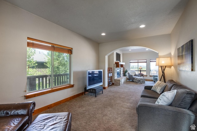 carpeted living area with arched walkways, recessed lighting, a textured ceiling, and baseboards