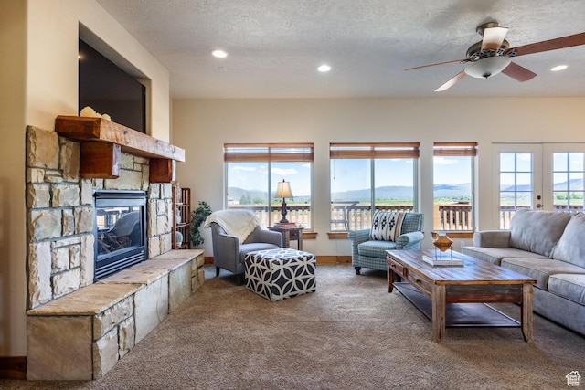 carpeted living area featuring a wealth of natural light, a mountain view, a fireplace, and ceiling fan