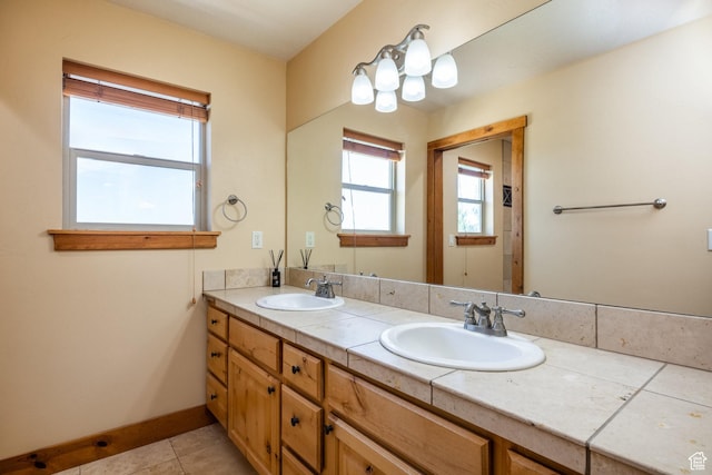 full bathroom featuring tile patterned flooring, double vanity, baseboards, and a sink