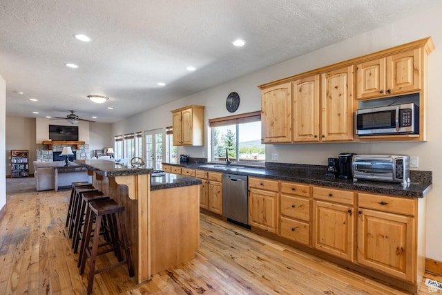 kitchen featuring a breakfast bar, light wood-style flooring, a toaster, stainless steel appliances, and a center island
