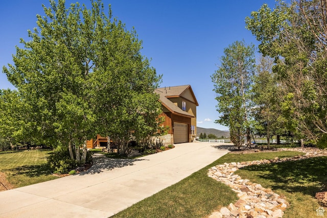 exterior space with stone siding, driveway, and a front lawn