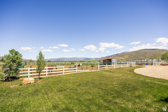 view of yard with an enclosed area, a mountain view, and a rural view
