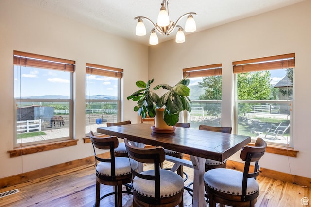 dining space featuring a notable chandelier, baseboards, visible vents, and light wood finished floors