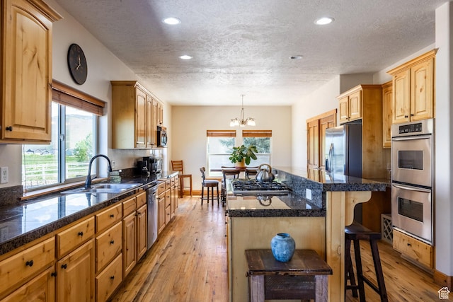 kitchen featuring a center island, tile counters, a breakfast bar, stainless steel appliances, and a sink