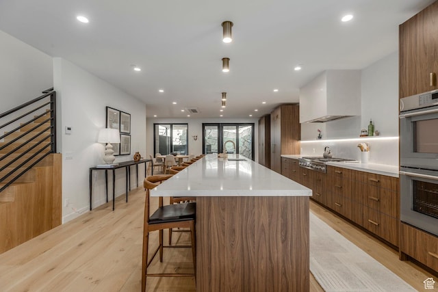 1063 Lowell Ave Unit 1, Park City, UT 84060 - kitchen featuring modern cabinets, stainless steel appliances, light wood-style flooring, a breakfast bar area, and brown cabinets