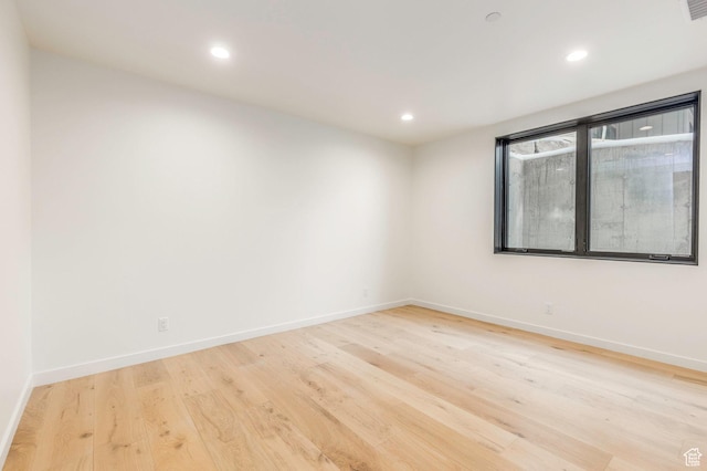spare room featuring recessed lighting, light wood-style floors, and baseboards