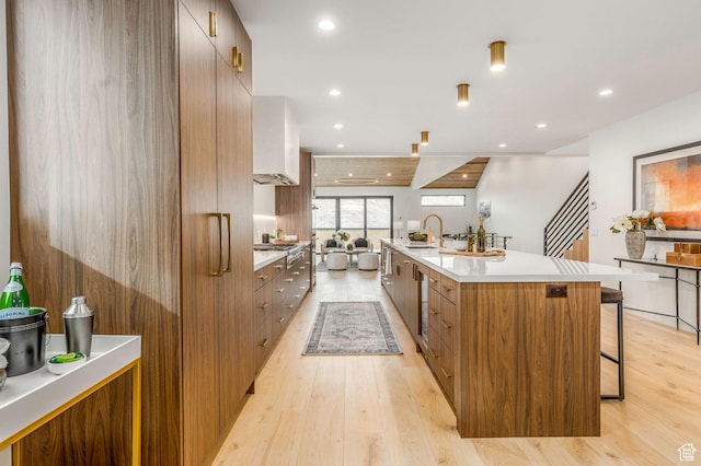 kitchen featuring light countertops, light wood finished floors, a breakfast bar area, and modern cabinets
