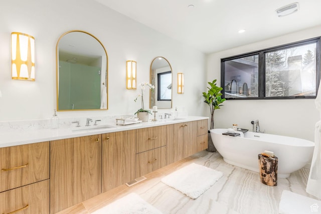 full bath with a sink, a freestanding bath, and double vanity