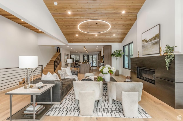 living room with stairs, a glass covered fireplace, wood finished floors, and wood ceiling