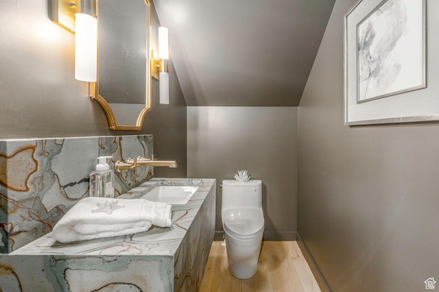 half bath featuring decorative backsplash, a sink, toilet, and wood finished floors