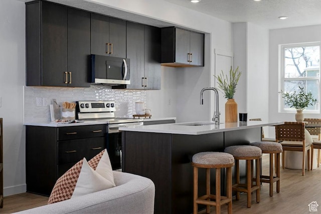 439 N 268 W Unit 4-18, Salt Lake City, UT 84103 - kitchen with stainless steel appliances, a sink, dark cabinets, a breakfast bar area, and tasteful backsplash