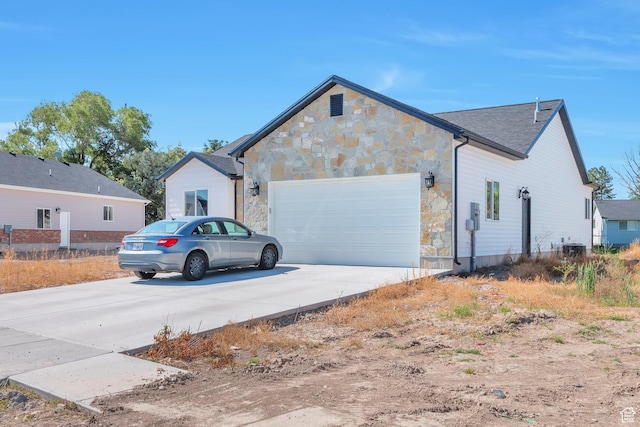 1118 E 1310 S, Garland, UT 84312 - view of property exterior featuring an attached garage, concrete driveway, and stone siding
