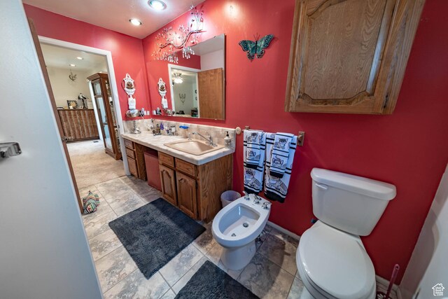 2317 N Hillside Dr, Wellington, UT 84542 - bathroom featuring a sink, double vanity, toilet, baseboards, and a bidet