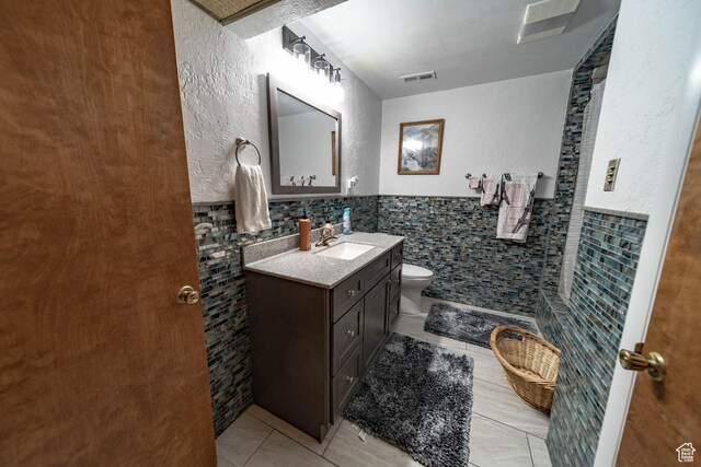2317 N Hillside Dr, Wellington, UT 84542 - bathroom with tile patterned floors, toilet, tile walls, visible vents, and vanity