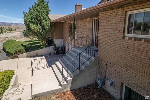 2317 N Hillside Dr, Wellington, UT 84542 - view of side of home featuring a patio area, a chimney, brick siding, and a mountain view