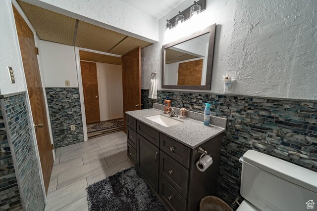 2317 N Hillside Dr, Wellington, UT 84542 - bathroom with tile patterned flooring, toilet, vanity, and a wainscoted wall
