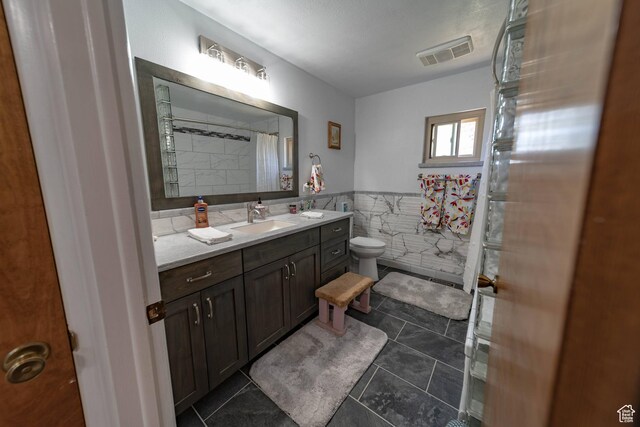 2317 N Hillside Dr, Wellington, UT 84542 - full bath featuring toilet, tile walls, visible vents, tile patterned flooring, and vanity
