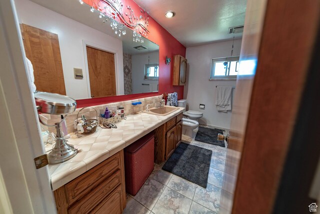 2317 N Hillside Dr, Wellington, UT 84542 - bathroom featuring a sink, double vanity, toilet, visible vents, and backsplash
