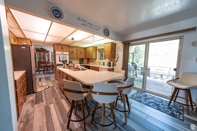 2317 N Hillside Dr, Wellington, UT 84542 - kitchen with brown cabinets, light countertops, dark wood-type flooring, freestanding refrigerator, and a center island