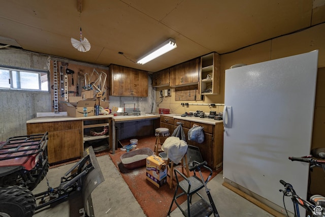 2317 N Hillside Dr, Wellington, UT 84542 - kitchen featuring open shelves, brown cabinetry, light countertops, and concrete flooring