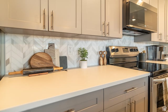 kitchen featuring tasteful backsplash, gray cabinetry, and appliances with stainless steel finishes