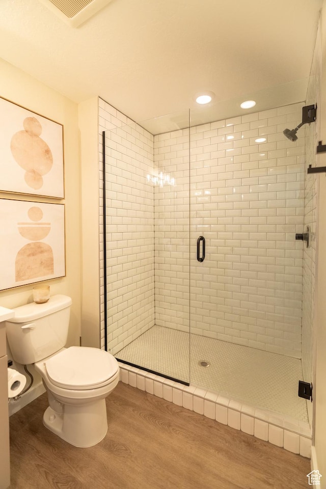 bathroom with wood-type flooring, toilet, and walk in shower