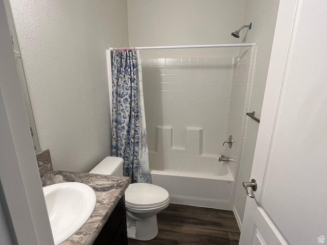bathroom featuring toilet, wood finished floors, shower / tub combo, a textured wall, and vanity