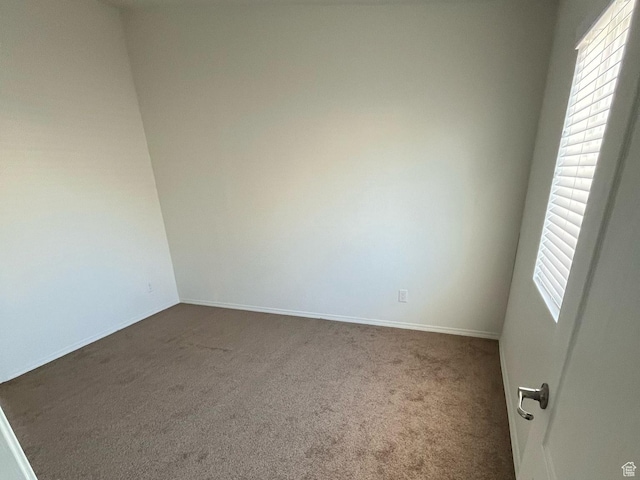 empty room featuring baseboards and dark carpet