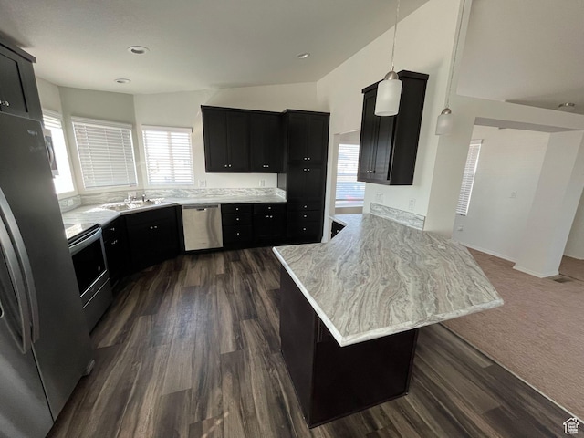 kitchen featuring appliances with stainless steel finishes, a peninsula, dark cabinetry, dark wood-style floors, and a sink