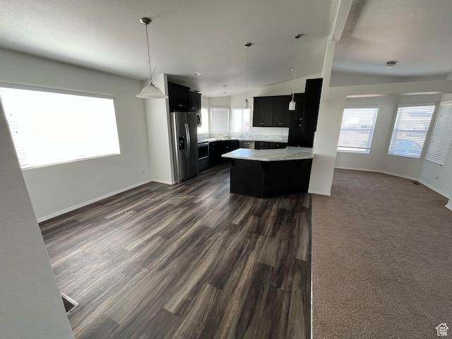 kitchen with plenty of natural light, dark cabinetry, open floor plan, stainless steel fridge with ice dispenser, and light countertops