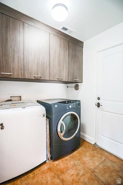 clothes washing area with cabinets and washing machine and clothes dryer