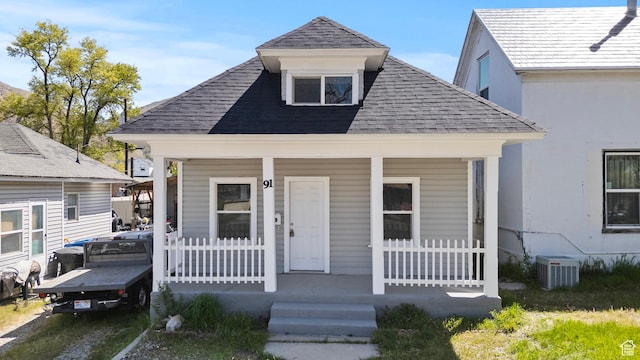view of front of home featuring cooling unit, roof with shingles, and covered porch