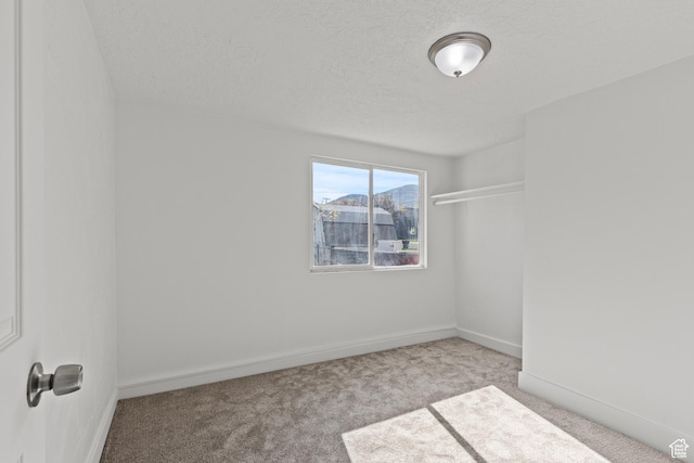 carpeted spare room with baseboards and a textured ceiling