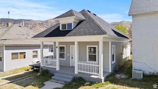view of front of house featuring a mountain view, a porch, roof with shingles, and cooling unit
