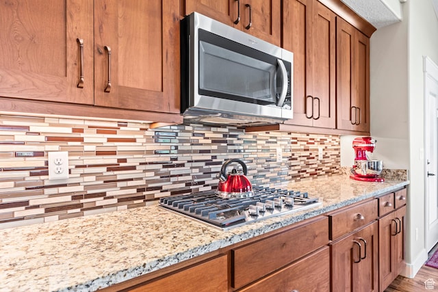 84 W 2100 N, Kamas, UT 84036 - kitchen featuring appliances with stainless steel finishes, brown cabinetry, light stone countertops, and tasteful backsplash