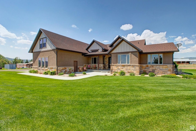 view of front of property featuring board and batten siding, a front yard, stone siding, and a shingled roof