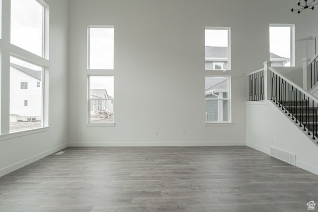 unfurnished living room featuring a towering ceiling and hardwood / wood-style flooring