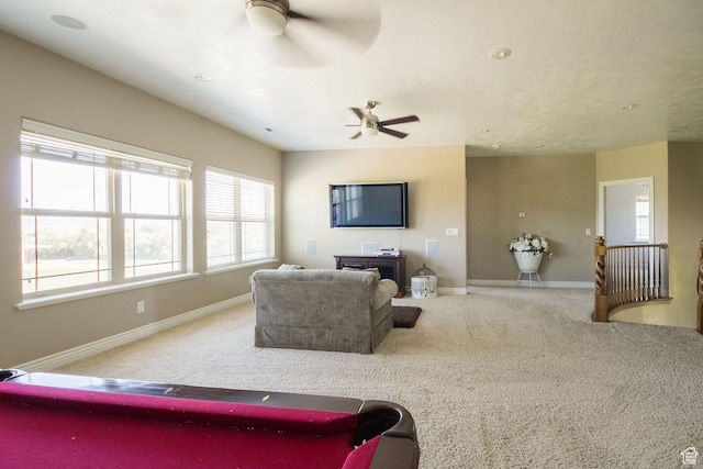 living area featuring baseboards, a ceiling fan, and carpet floors