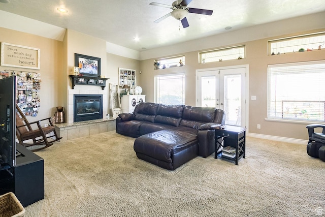 living room featuring a tiled fireplace, ceiling fan, carpet flooring, and a healthy amount of sunlight