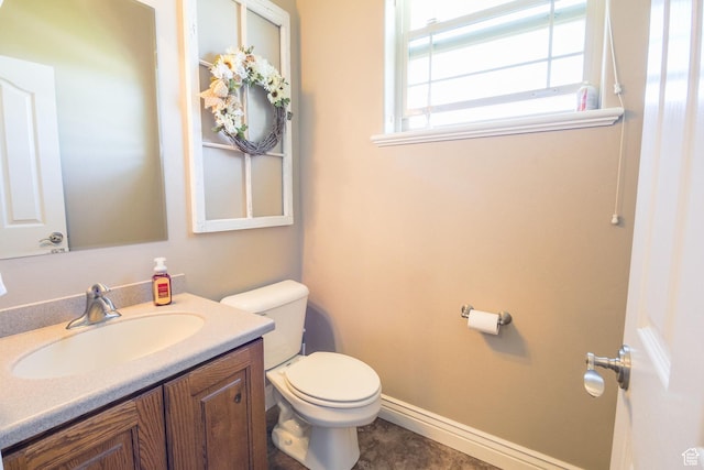 half bathroom with vanity, baseboards, and toilet