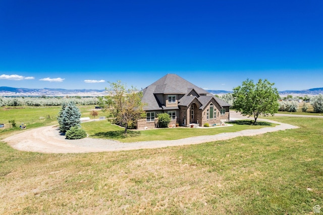 view of front facade with a front yard, a mountain view, and a shingled roof