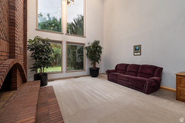 living room featuring a chandelier, carpet floors, a high ceiling, and baseboards