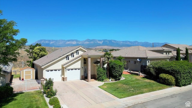 single story home with a mountain view, a garage, a storage shed, and a front yard