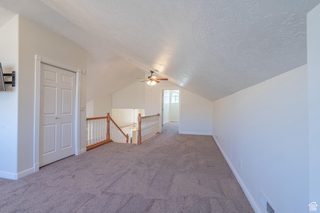 additional living space featuring light carpet, a textured ceiling, vaulted ceiling, and ceiling fan