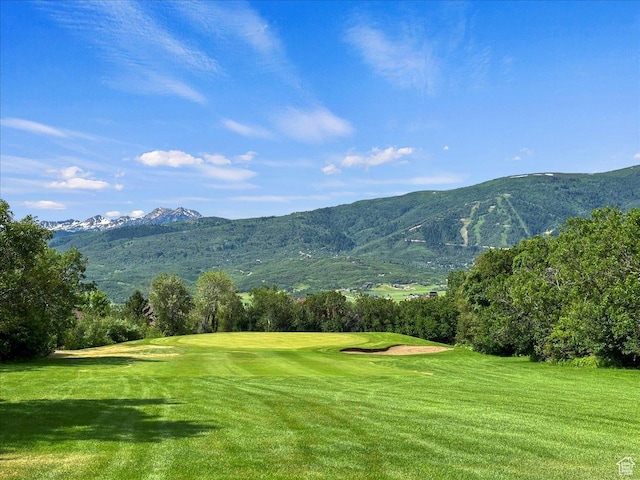 view of community featuring golf course view, a mountain view, and a lawn