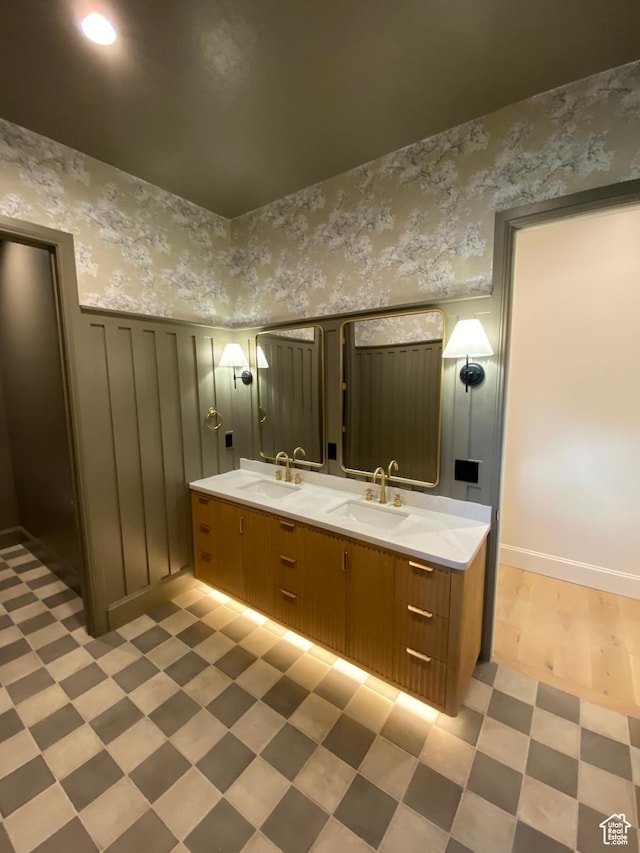 full bath featuring wainscoting, tile patterned floors, a sink, and double vanity