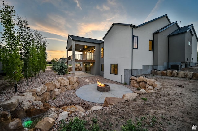 213 W 250 S Unit 15, Mapleton, UT 84664 - back of house at dusk featuring an outdoor fire pit, a patio, central air condition unit, a balcony, and stucco siding